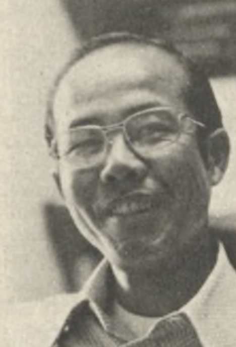 A black and white photograph of an Asian man wearing glasses and a collared shirt, smiling at the camera. 