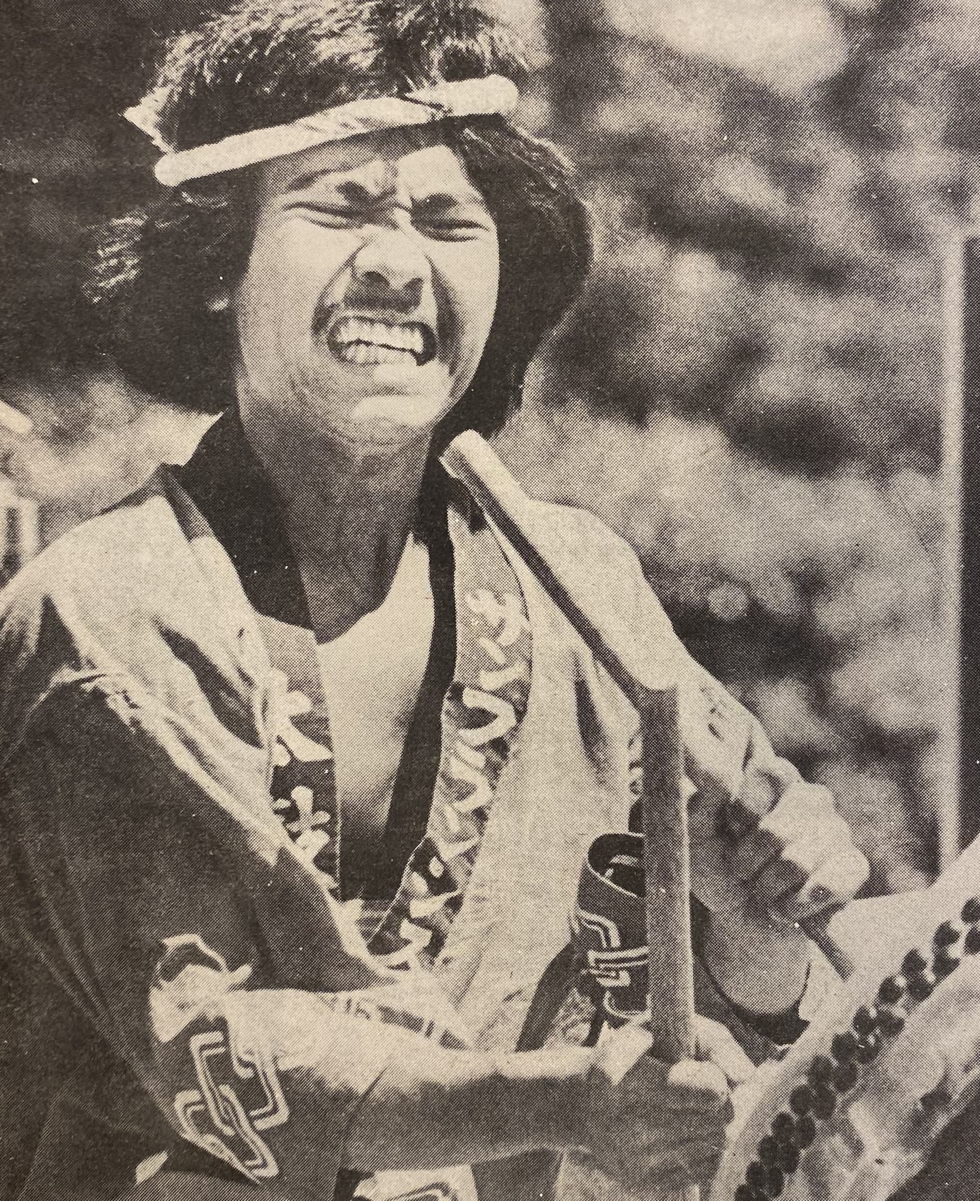 A person passionately playing a taiko drum, wearing a traditional headband and robe, with an intense facial expression. 