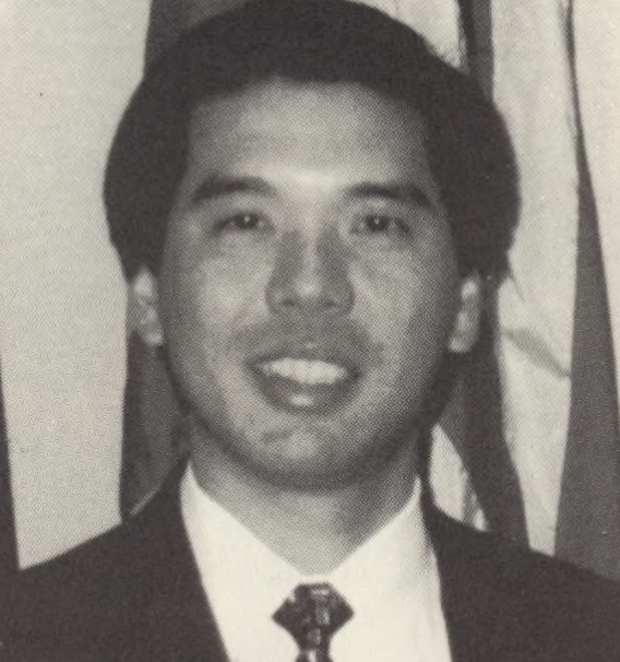 Michael Chang. (APALI opening ceremony program, 1997) A grayscale image of a man in a suit and tie, smiling at the camera.