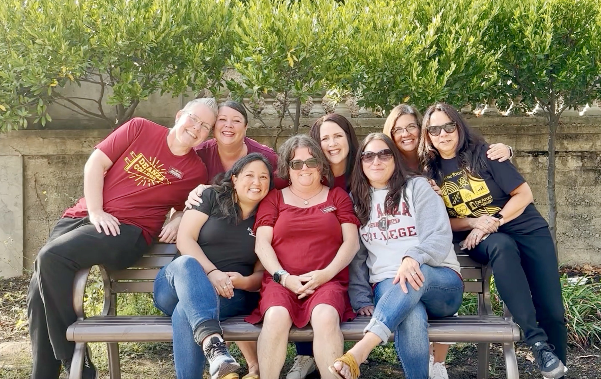 DHHS group picture of staff interpreters and captioners on a bench wearing DeAnza shirts