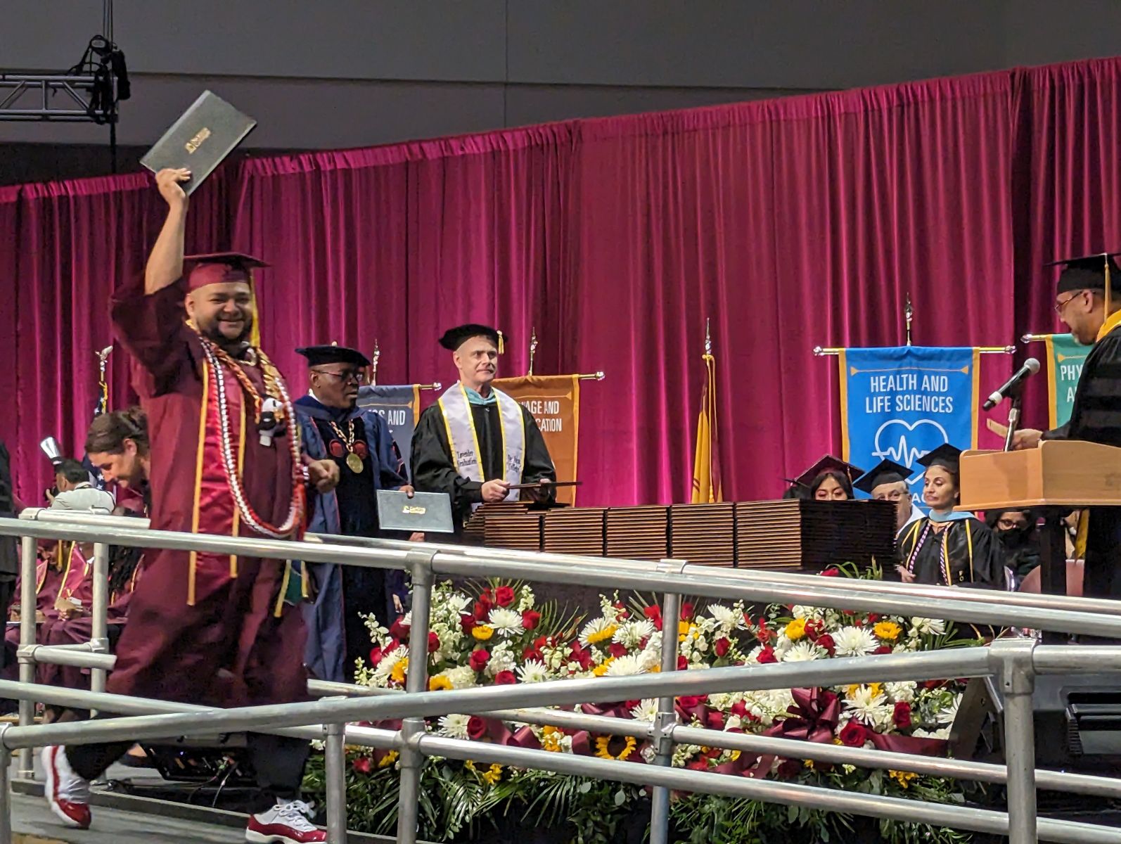 DHHS student holding his diploma up the the air with a big smile