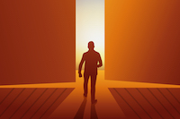 silhouette of man walking toward light seen through opening