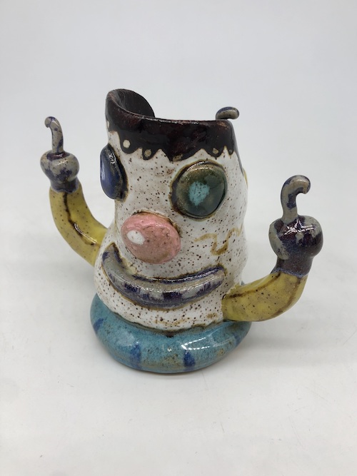 sculpture of comical figure raising two hands with  in air