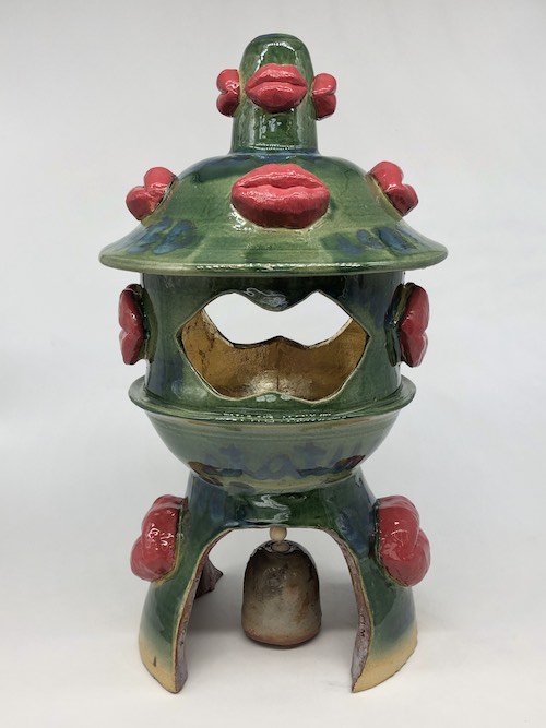 green sculpture with several red lips or mouths