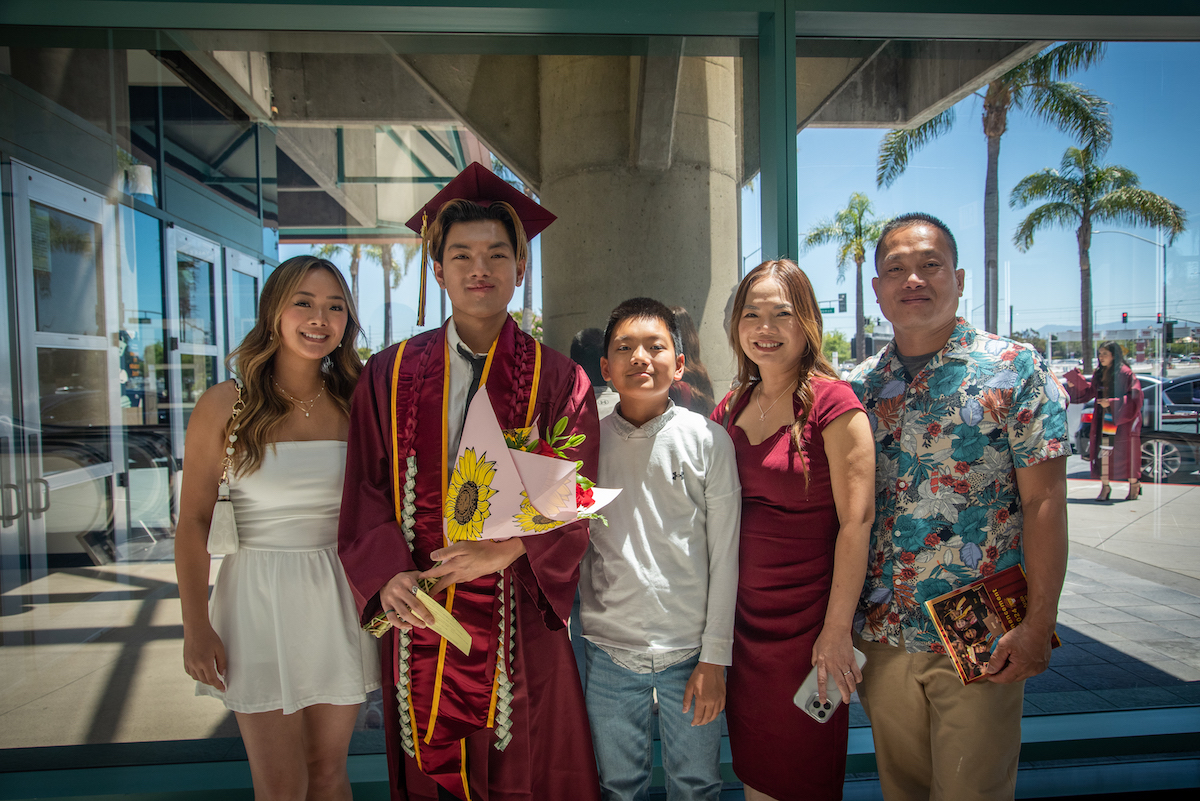 young man in grad cap with family members