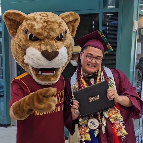 Person in Mountain Lion costume with graduating student holding diploma