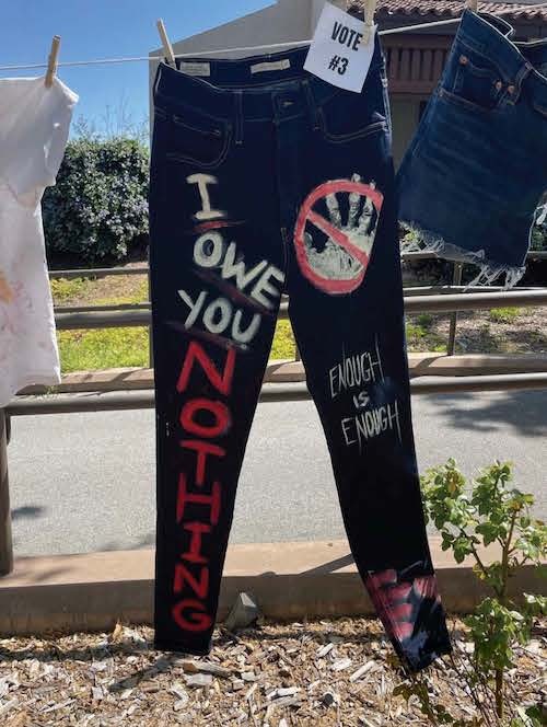 blue jeans painted with message: "I owe you nothing"