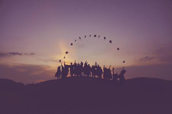 silhouettes of graduating students on hilltop